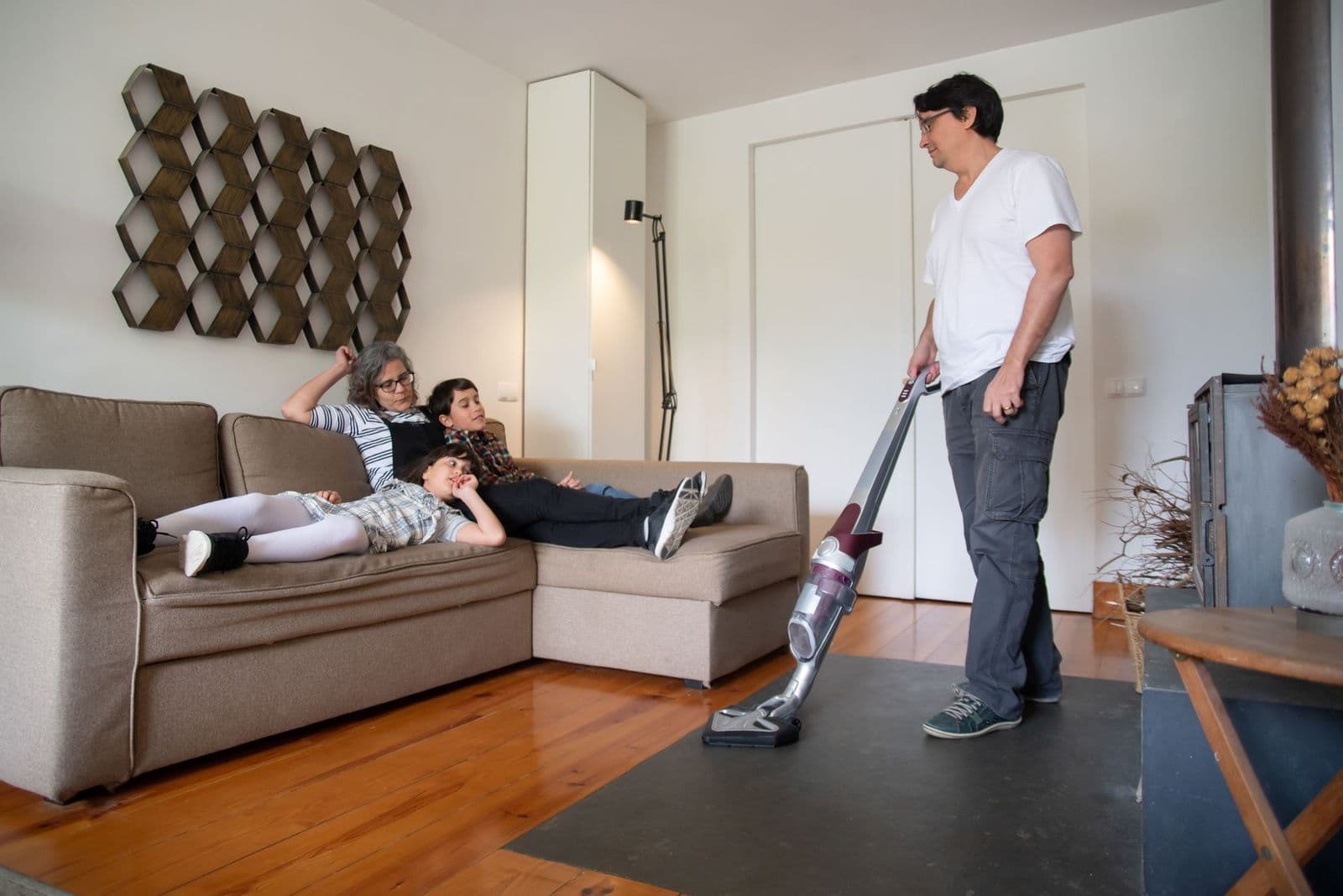 Person vacuuming a carpet at home, illustrating how long does a vacuum cleaner last