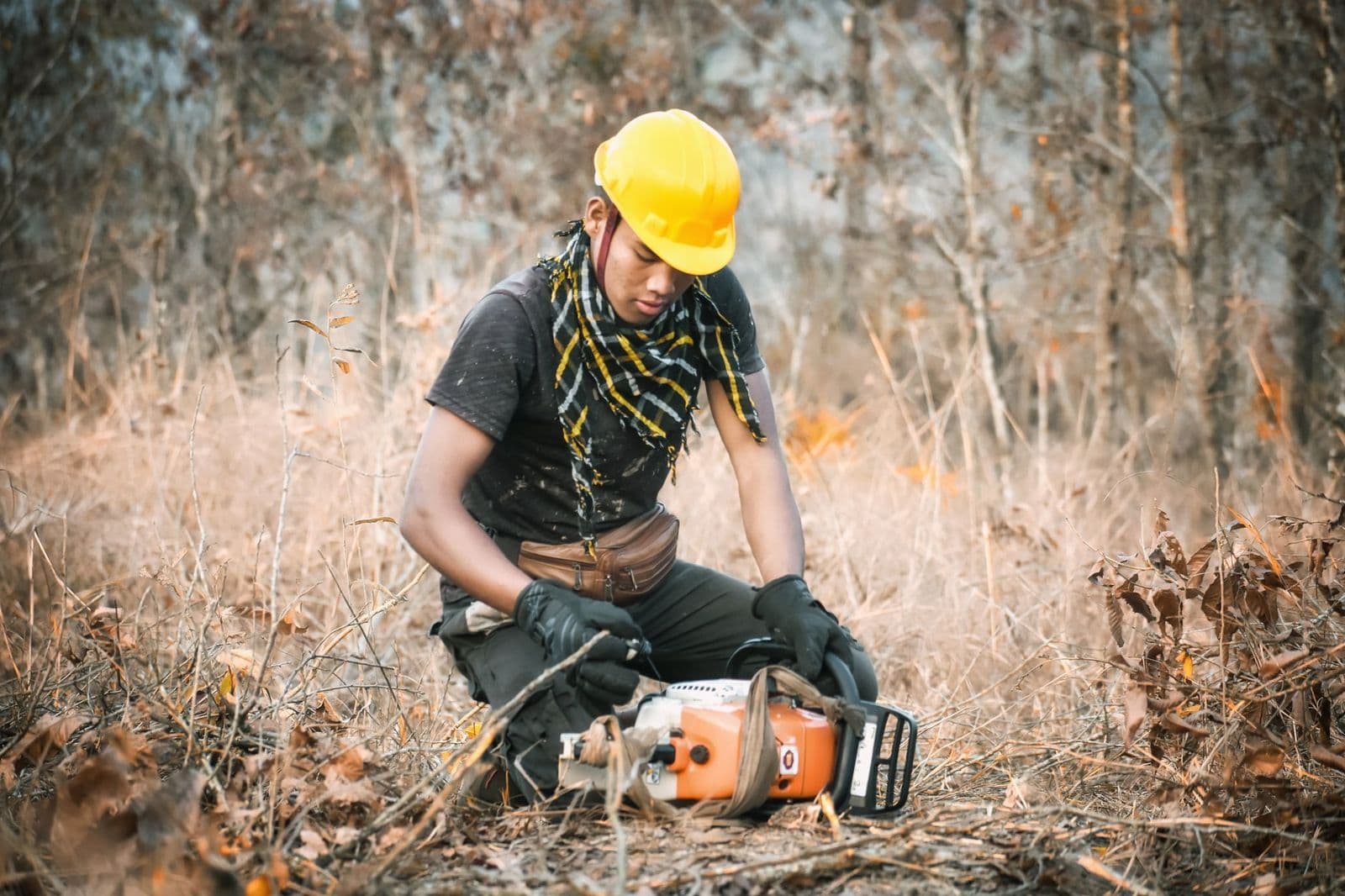 Man in safety gear checking a chainsaw outdoors, showing how to clean a chainsaw