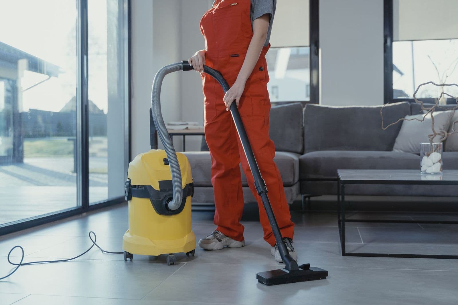 Cleaner vacuuming a living room floor, showing how to use a vacuum cleaner