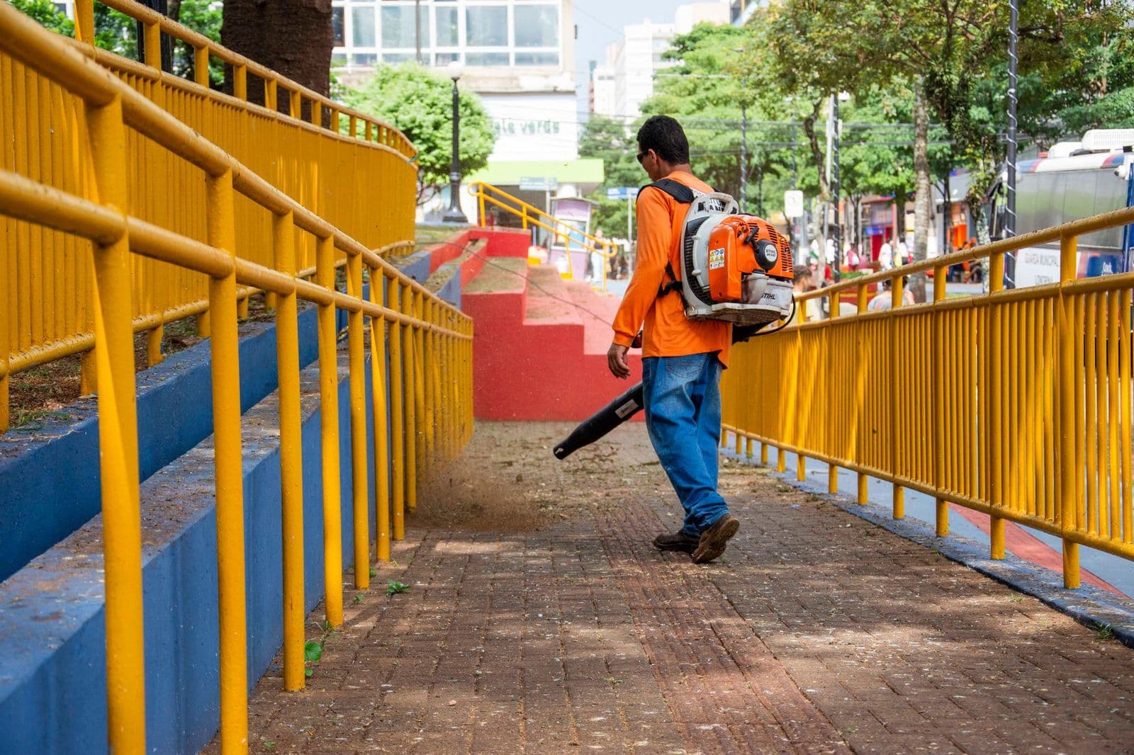 Worker clearing a sidewalk with a leaf blower, showing how does a leaf blower work